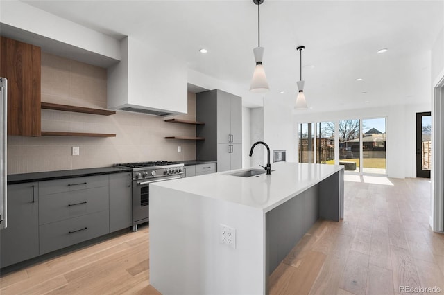 kitchen featuring decorative light fixtures, high end stainless steel range, light hardwood / wood-style floors, and sink