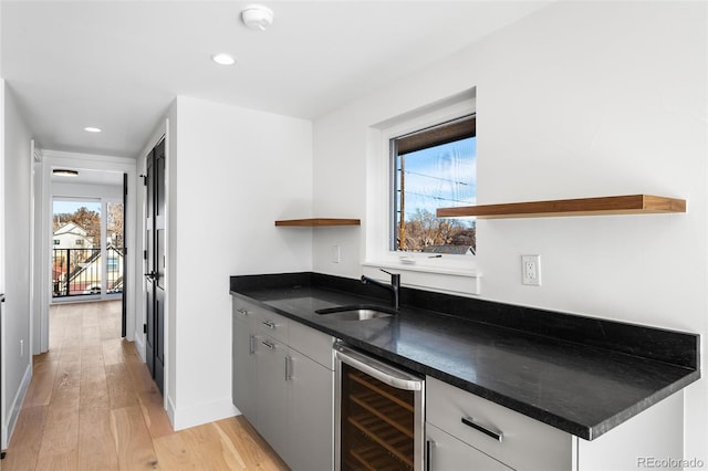 kitchen with light hardwood / wood-style floors, white cabinetry, sink, and wine cooler