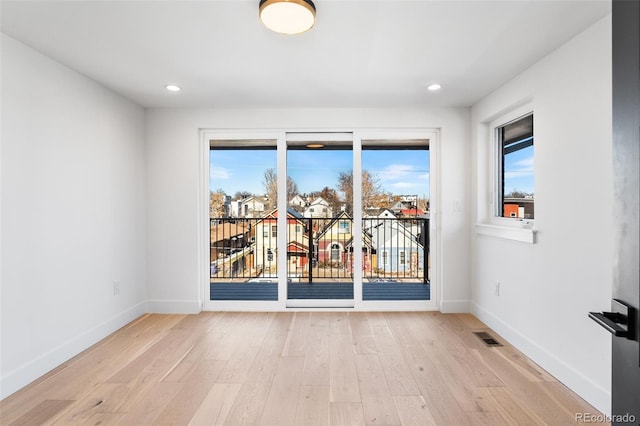 spare room featuring a healthy amount of sunlight and light hardwood / wood-style floors