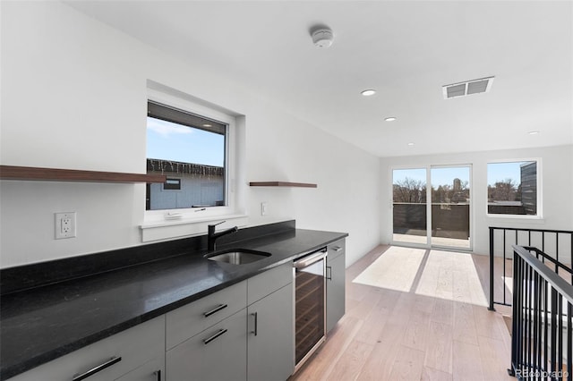 kitchen with gray cabinets, sink, beverage cooler, and light hardwood / wood-style flooring