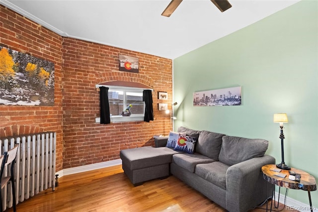 1450 N High St Unit 3, Denver, CO 80218 - living area with radiator, a ceiling fan, wood finished floors, brick wall, and a fireplace