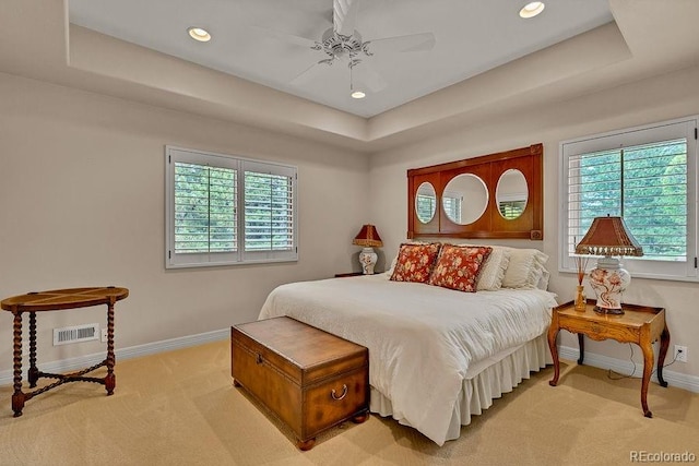 bedroom featuring light colored carpet, baseboards, a tray ceiling, recessed lighting, and ceiling fan