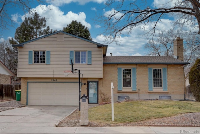 split level home with a chimney, fence, a front lawn, and brick siding