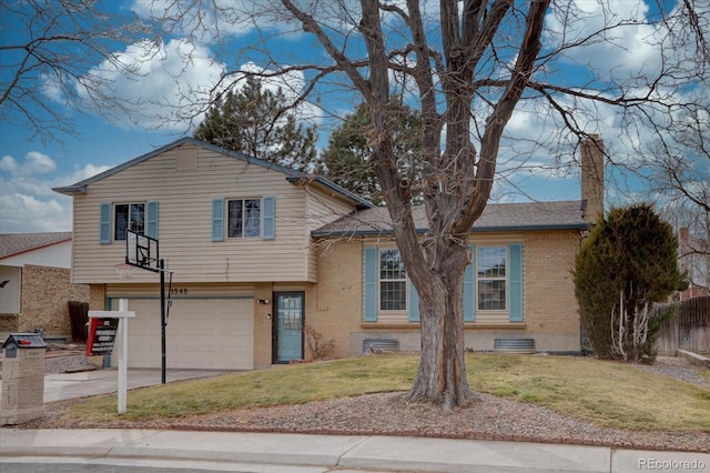 tri-level home featuring a front yard, concrete driveway, brick siding, and fence