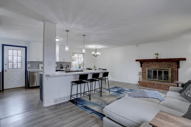 living area with light wood-style flooring, plenty of natural light, visible vents, and a brick fireplace