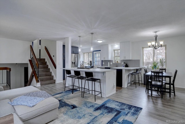 kitchen with light wood-style floors, light countertops, stainless steel refrigerator with ice dispenser, and a breakfast bar area