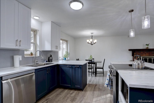 kitchen featuring stainless steel appliances, a peninsula, a sink, light countertops, and blue cabinetry