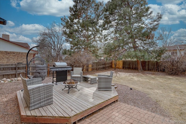 wooden terrace with a patio area, a fenced backyard, a grill, and a fire pit