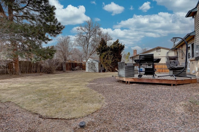 view of yard featuring a storage shed, a deck, an outdoor structure, and fence