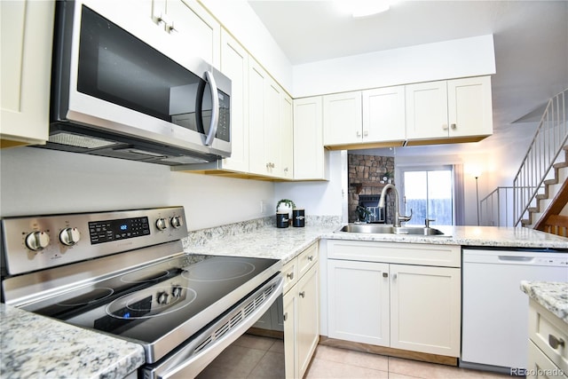 kitchen with stainless steel appliances, white cabinetry, and a sink