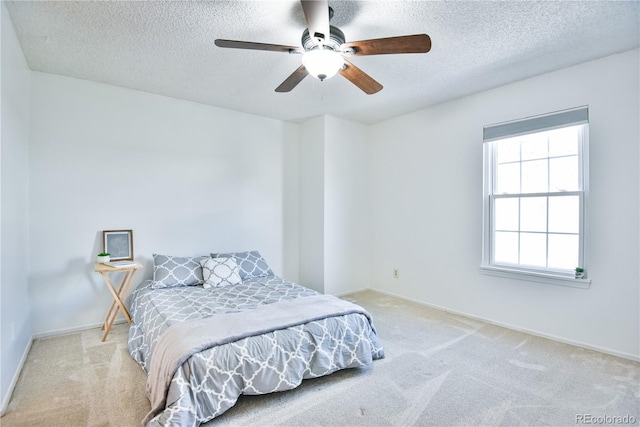 bedroom with light carpet, ceiling fan, a textured ceiling, and baseboards