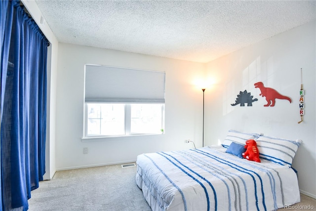 bedroom with light colored carpet, visible vents, a textured ceiling, and baseboards