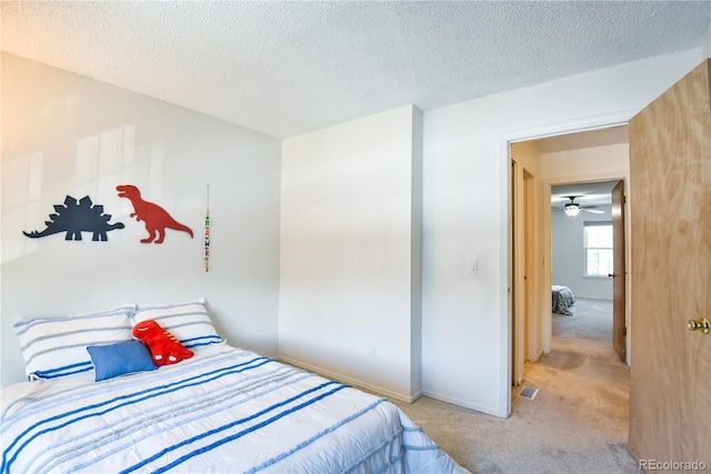 bedroom featuring light carpet, visible vents, baseboards, and a textured ceiling