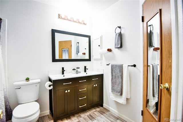 full bath featuring double vanity, wood finished floors, toilet, and baseboards