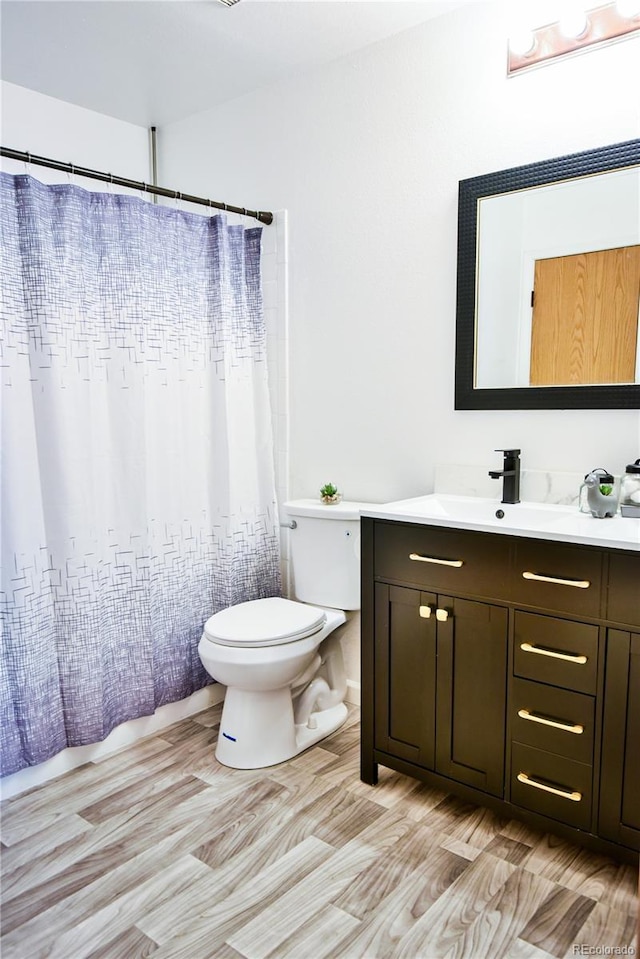 bathroom featuring toilet, wood finished floors, and vanity