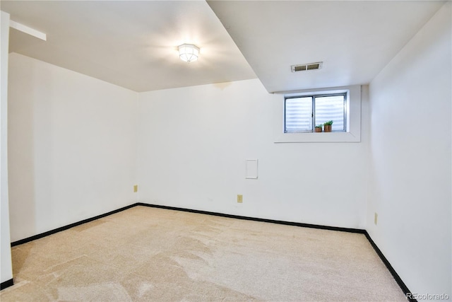 spare room featuring light carpet, visible vents, and baseboards