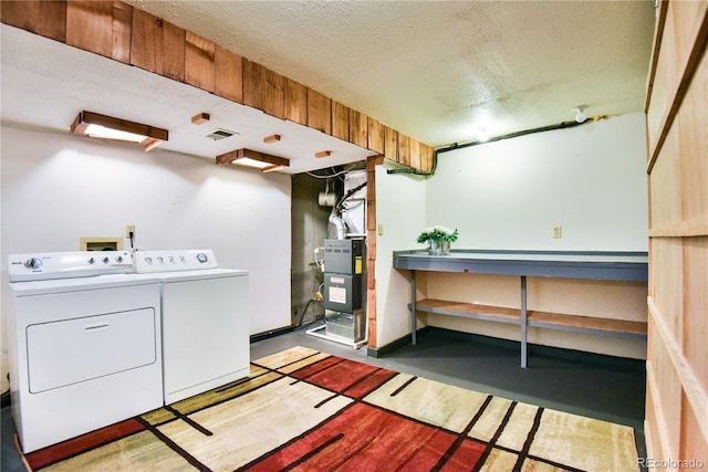 clothes washing area featuring a textured ceiling, laundry area, and washing machine and clothes dryer