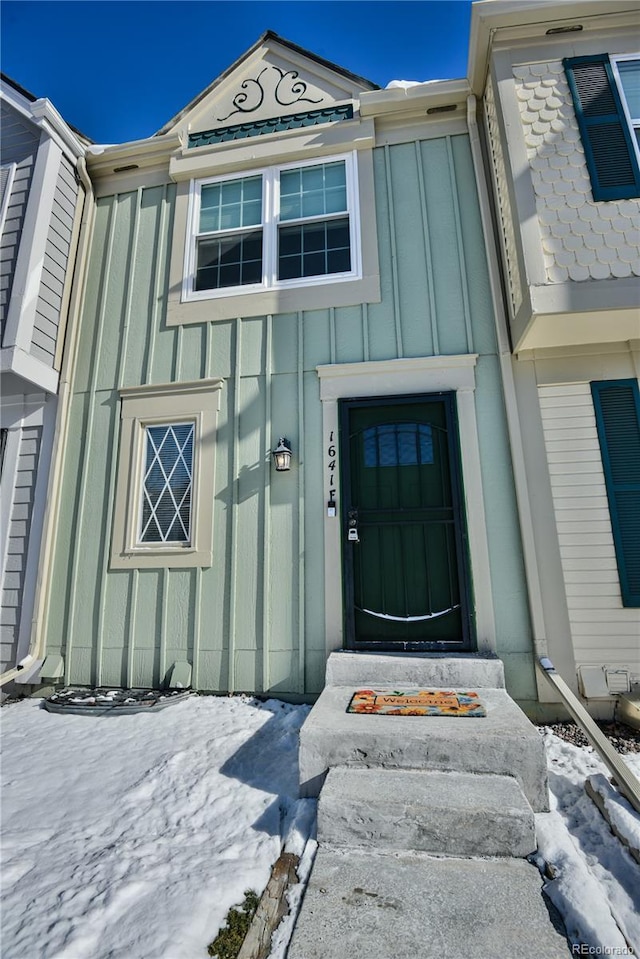 snow covered property entrance with board and batten siding