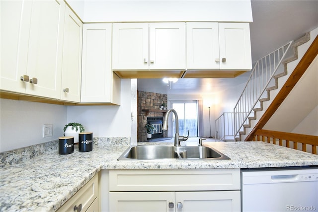 1641 S Idalia Cir Unit F, Aurora, CO 80017 - kitchen featuring dishwasher, a sink, white cabinets, light stone countertops, and a stone fireplace