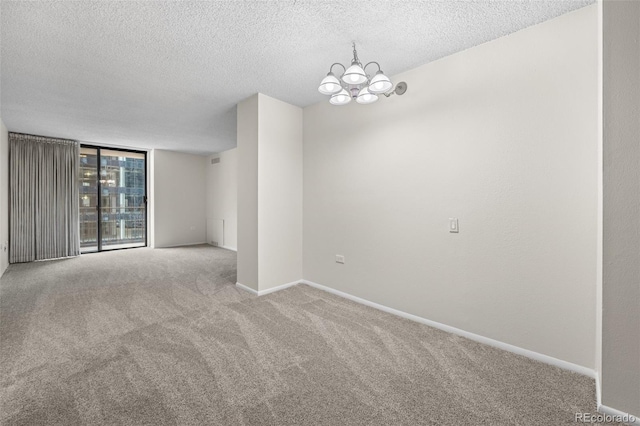 empty room featuring a notable chandelier, carpet floors, floor to ceiling windows, and a textured ceiling