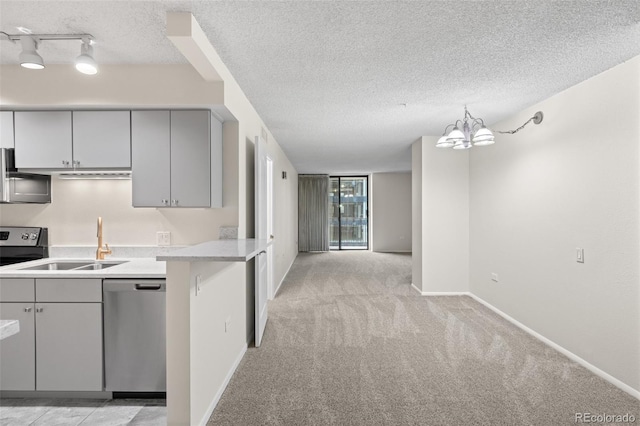 kitchen with a textured ceiling, stainless steel dishwasher, gray cabinets, light carpet, and sink