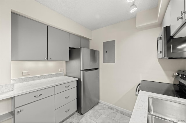 kitchen featuring appliances with stainless steel finishes, gray cabinets, a textured ceiling, electric panel, and light tile patterned flooring