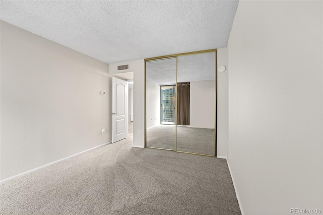 unfurnished bedroom featuring carpet, a closet, and a textured ceiling