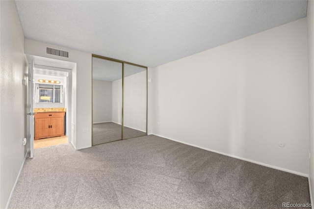 unfurnished bedroom featuring light carpet, a closet, and a textured ceiling