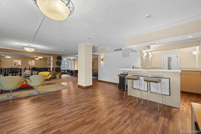 living room with wood-type flooring, ornamental molding, and a textured ceiling