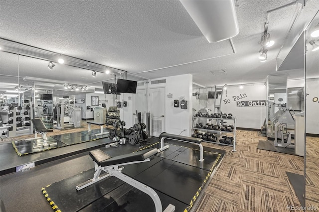 exercise room featuring track lighting and a textured ceiling