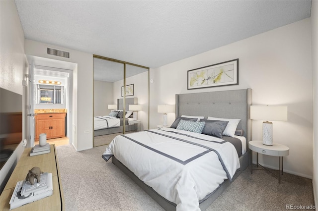 bedroom featuring light colored carpet, ensuite bathroom, a closet, and a textured ceiling