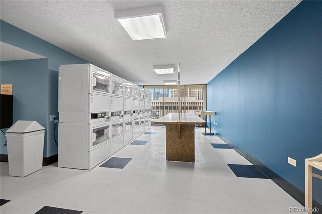 kitchen with white cabinetry, floor to ceiling windows, stacked washing maching and dryer, a textured ceiling, and a center island