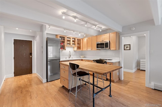 220 E Ln Bonte St Unit 317, Dillon, CO 80435 - kitchen with stainless steel appliances, a sink, light brown cabinetry, baseboards, and light wood-style floors