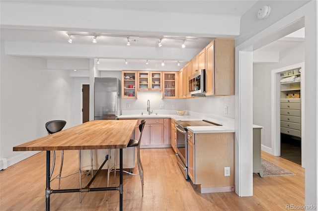 220 E Ln Bonte St Unit 317, Dillon, CO 80435 - kitchen with appliances with stainless steel finishes, a sink, light countertops, light wood-type flooring, and glass insert cabinets