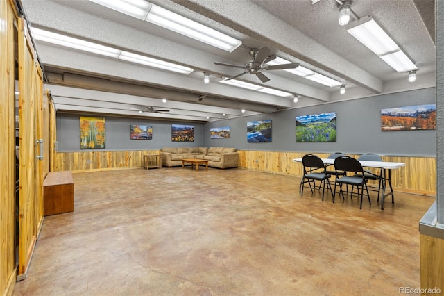 220 E Ln Bonte St Unit 317, Dillon, CO 80435 - dining area featuring wood walls, concrete flooring, a ceiling fan, a wainscoted wall, and beamed ceiling