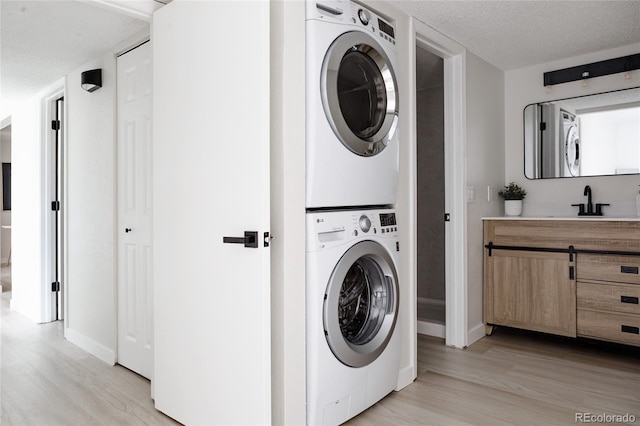 7395 E Eastman Ave Unit 202N, Denver, CO 80231 - laundry room with stacked washer / dryer, light wood-style floors, baseboards, and a textured ceiling