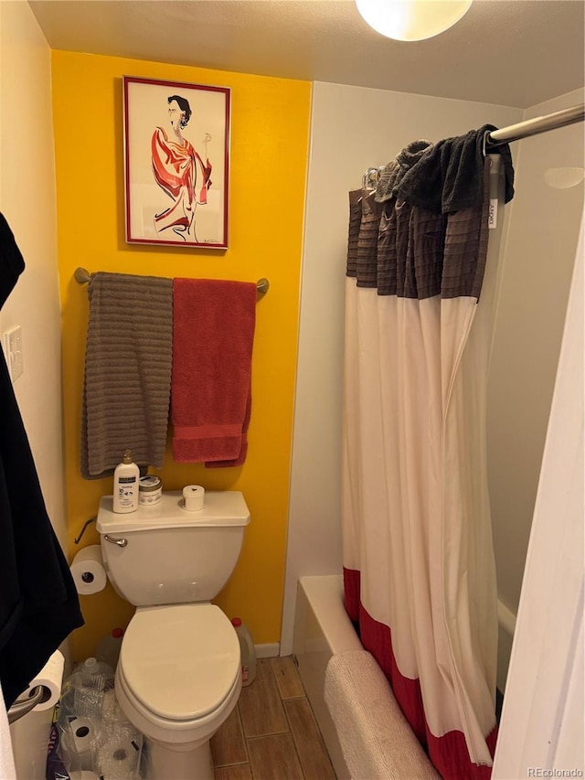 1888 S Jackson St Unit 404, Denver, CO 80210 - full bathroom featuring toilet, shower / bathtub combination with curtain, wood finished floors, and baseboards