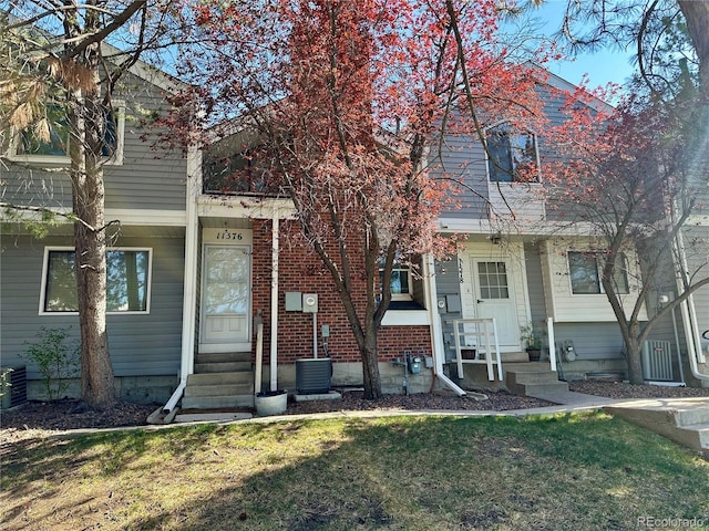 view of front facade featuring a front lawn, entry steps, and central AC