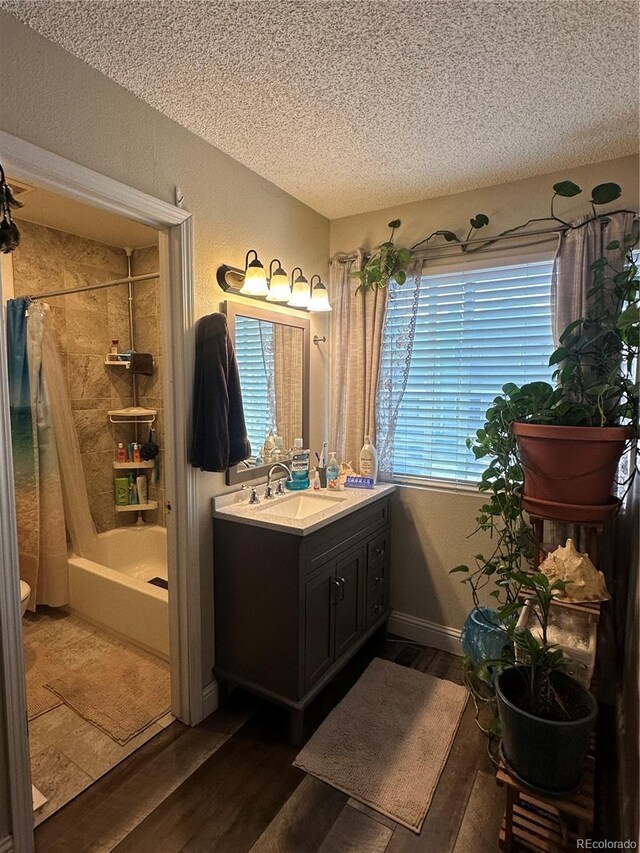 11576 E Bayaud Dr, Aurora, CO 80012 - bathroom featuring a textured ceiling, vanity, wood finished floors, and shower / bath combo with shower curtain