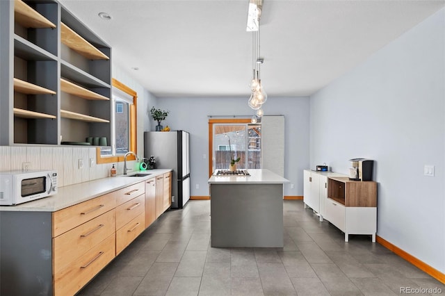 kitchen featuring decorative backsplash, appliances with stainless steel finishes, sink, decorative light fixtures, and a center island