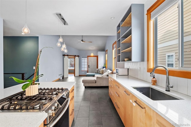 kitchen featuring pendant lighting, sink, gas range, ceiling fan, and light stone countertops