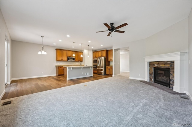 17710 E Emilia Dr, Parker, CO 80134 - unfurnished living room featuring dark carpet, a ceiling fan, recessed lighting, a stone fireplace, and dark wood finished floors