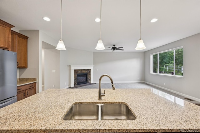 17710 E Emilia Dr, Parker, CO 80134 - kitchen with freestanding refrigerator, open floor plan, brown cabinetry, pendant lighting, and light stone countertops