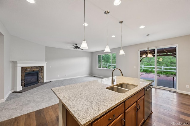 17710 E Emilia Dr, Parker, CO 80134 - kitchen with decorative light fixtures, a ceiling fan, brown cabinetry, stainless steel dishwasher, and an island with sink