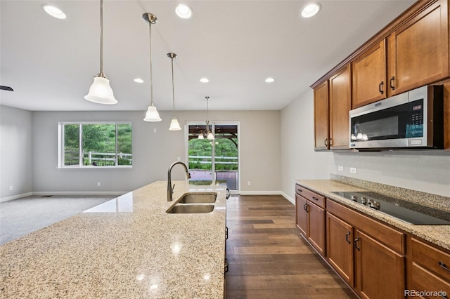 17710 E Emilia Dr, Parker, CO 80134 - kitchen with stainless steel microwave, black electric cooktop, decorative light fixtures, recessed lighting, and brown cabinets