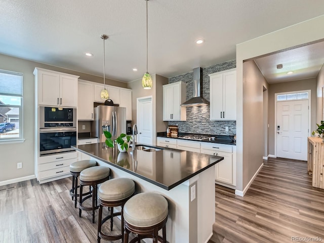 7702 E 157th Ave, Thornton, CO 80602 - kitchen with appliances with stainless steel finishes, wall chimney exhaust hood, dark countertops, backsplash, and wood finished floors
