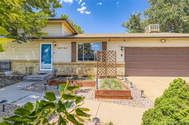 15705 E Brown Ave, Aurora, CO 80013 - view of front facade featuring brick siding, a garden, an attached garage, and driveway