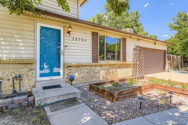 15705 E Brown Ave, Aurora, CO 80013 - property entrance with brick siding, an attached garage, and driveway
