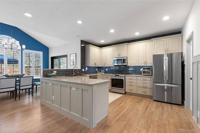 7106 Cerney Cir, Castle Pines, CO 80108 - kitchen with appliances with stainless steel finishes, a sink, a peninsula, decorative backsplash, and vaulted ceiling
