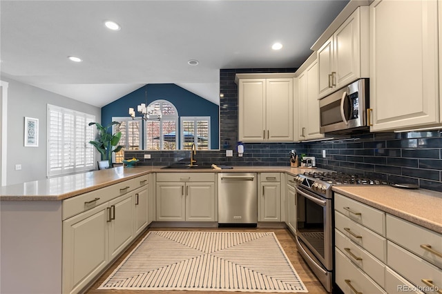 7106 Cerney Cir, Castle Pines, CO 80108 - kitchen featuring appliances with stainless steel finishes, a sink, a peninsula, decorative backsplash, and vaulted ceiling